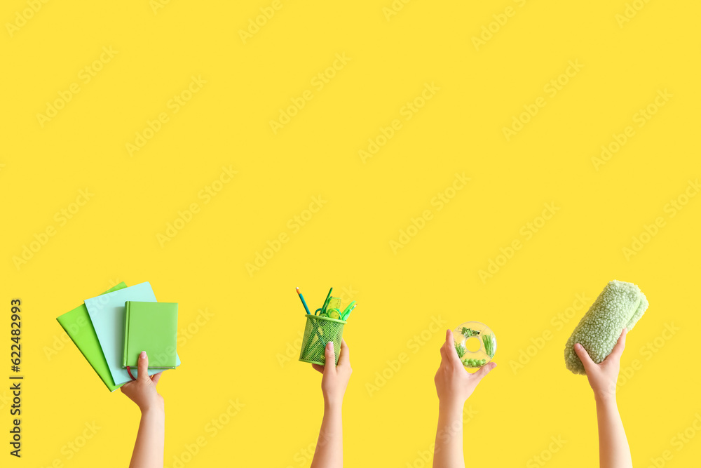 Female hands holding school supplies on yellow background