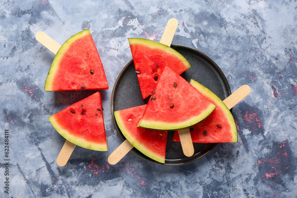 Plate with sweet watermelon sticks on blue background