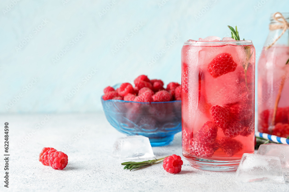 Glass and bottle of fresh raspberry lemonade with rosemary on white table