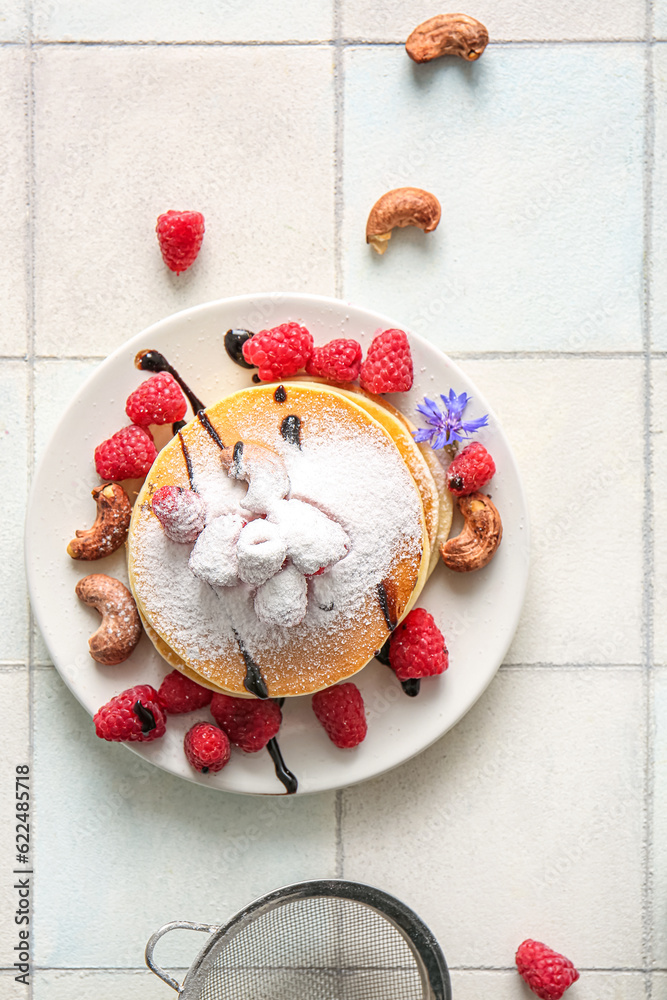 Plate of tasty pancakes with raspberries and nuts on white tile background