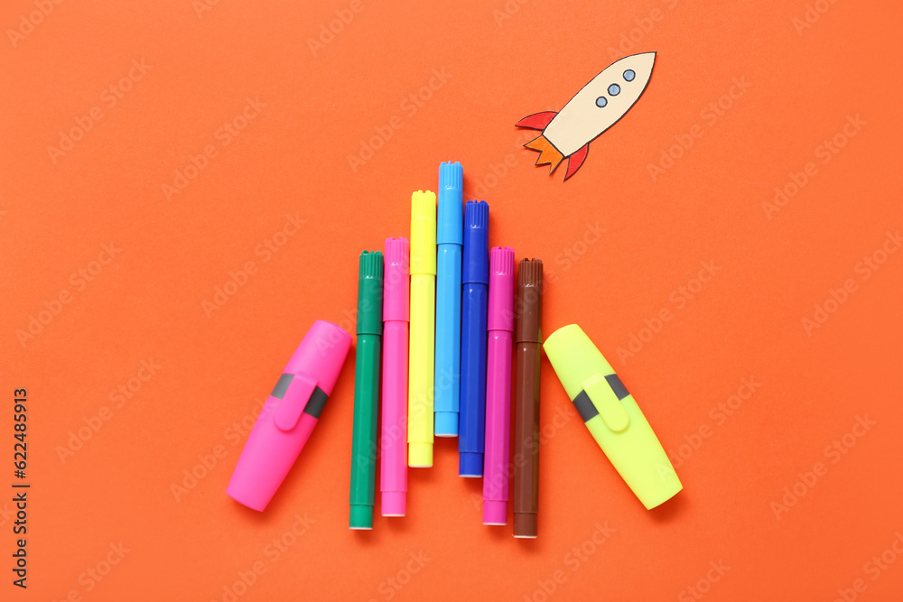 Markers with paper rocket on red background