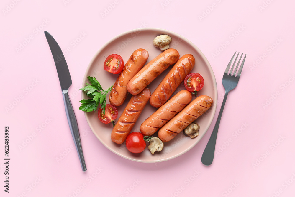 Plate with tasty grilled sausages on pink background