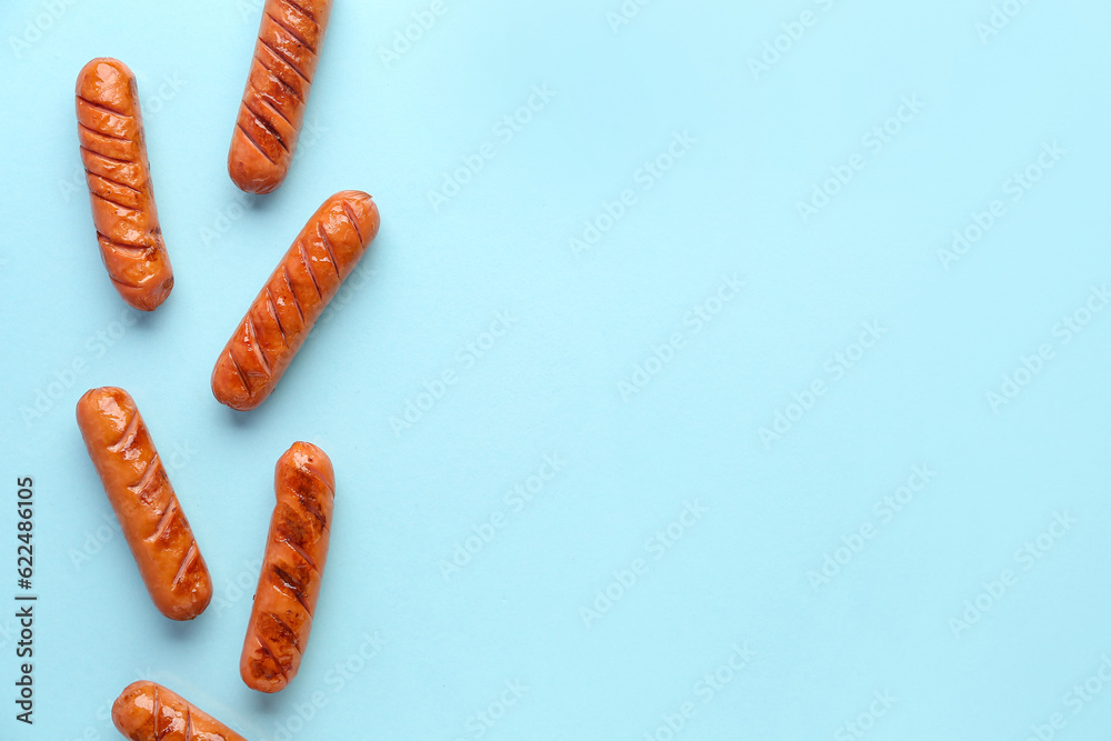 Tasty grilled sausages on blue background