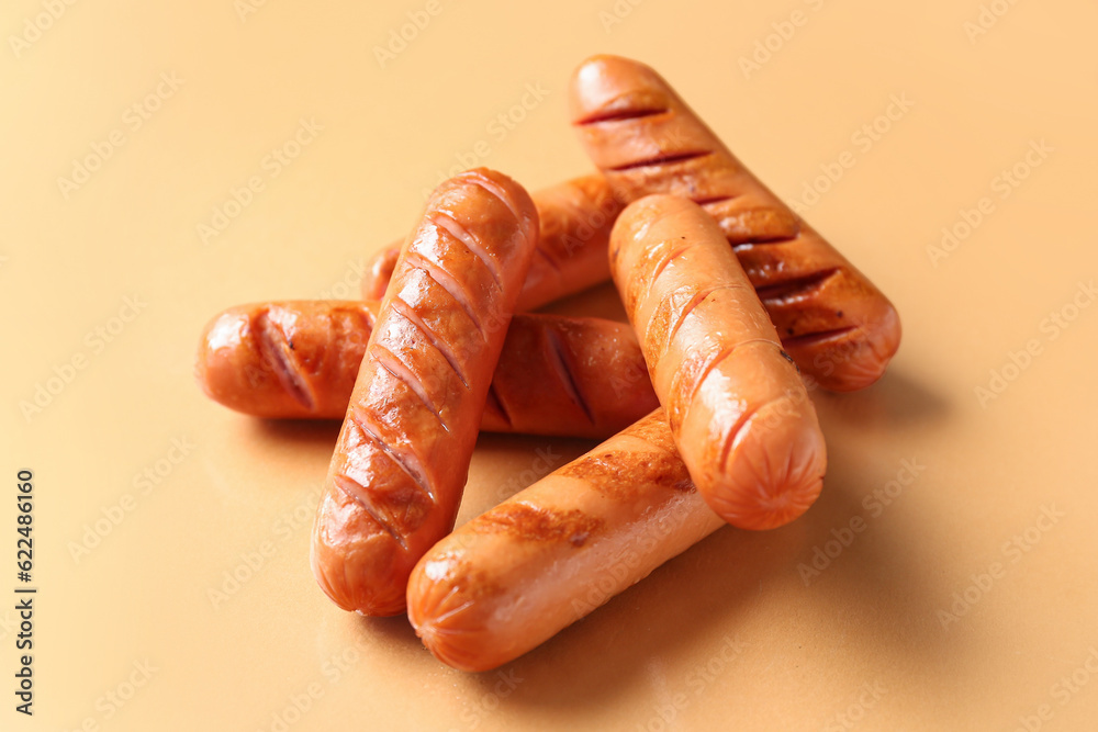 Tasty grilled sausages on orange background