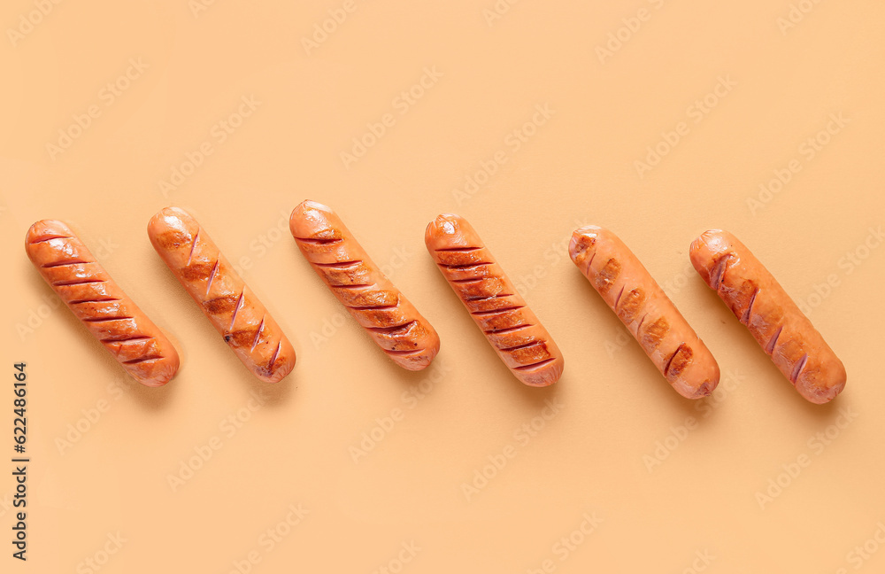 Tasty grilled sausages on orange background