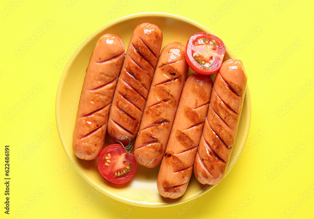 Plate with tasty grilled sausages on yellow background