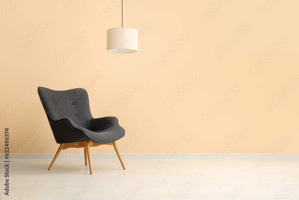 Stylish black armchair and lamp near beige wall