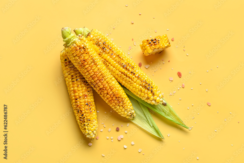 Tasty grilled corn cobs on yellow background