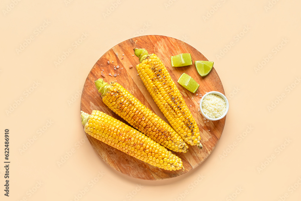 Wooden board with tasty grilled corn cobs and bowl of cheese on orange background