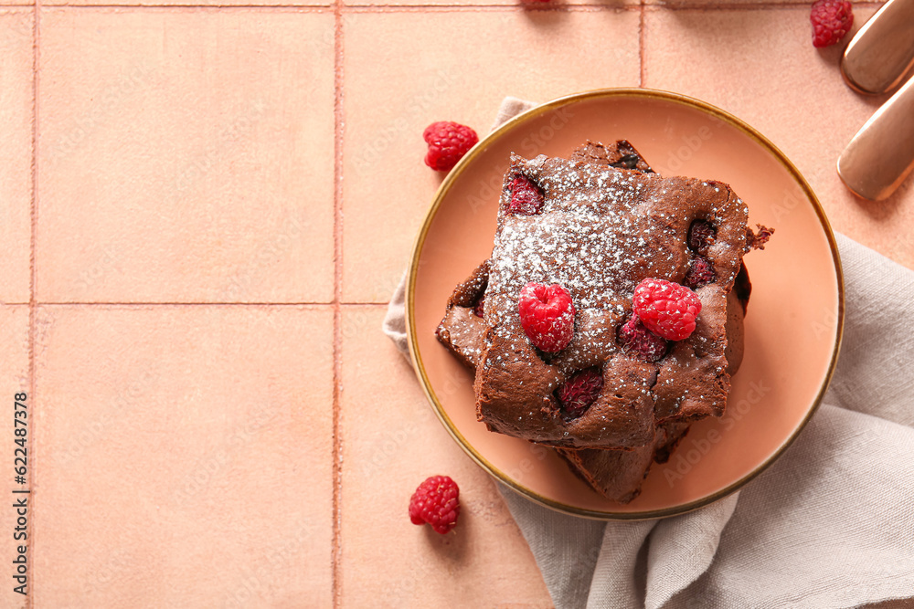 Plate with pieces of raspberry chocolate brownie on pink tile table