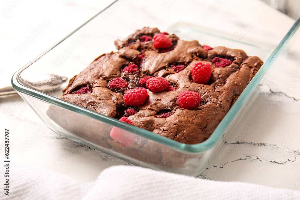 Baking dish with raspberry chocolate brownie on white background