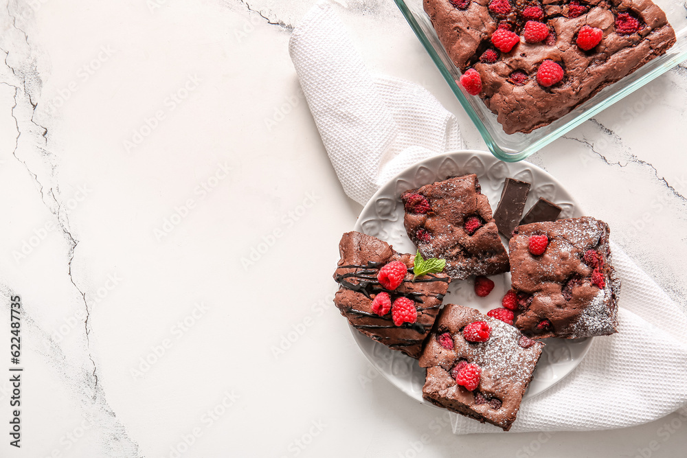 Plate and baking dish with raspberry chocolate brownie on white background