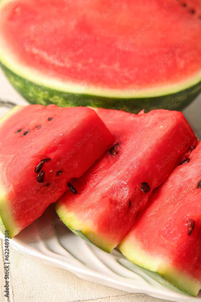 Half of fresh watermelon and plate with pieces on table, closeup