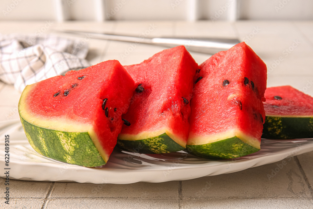 Plate with pieces of fresh watermelon on white tile table