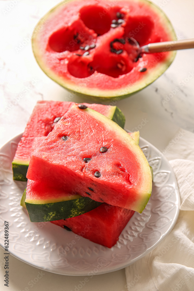 Half of fresh watermelon and plate with pieces on white table