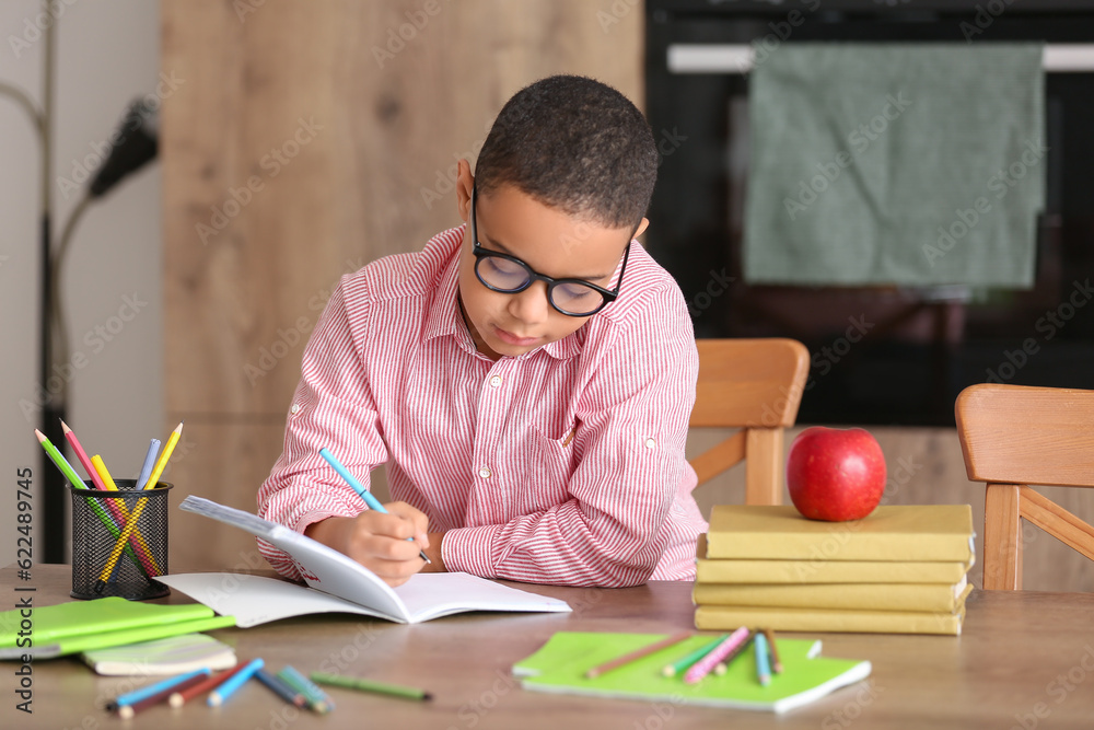 Little African-American boy doing homework in kitchen