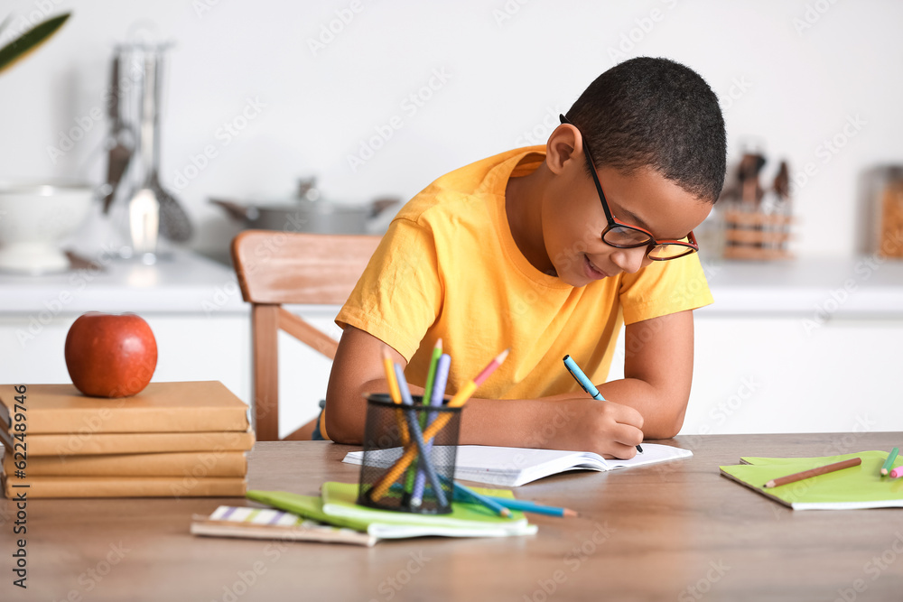 Little African-American boy doing homework in kitchen