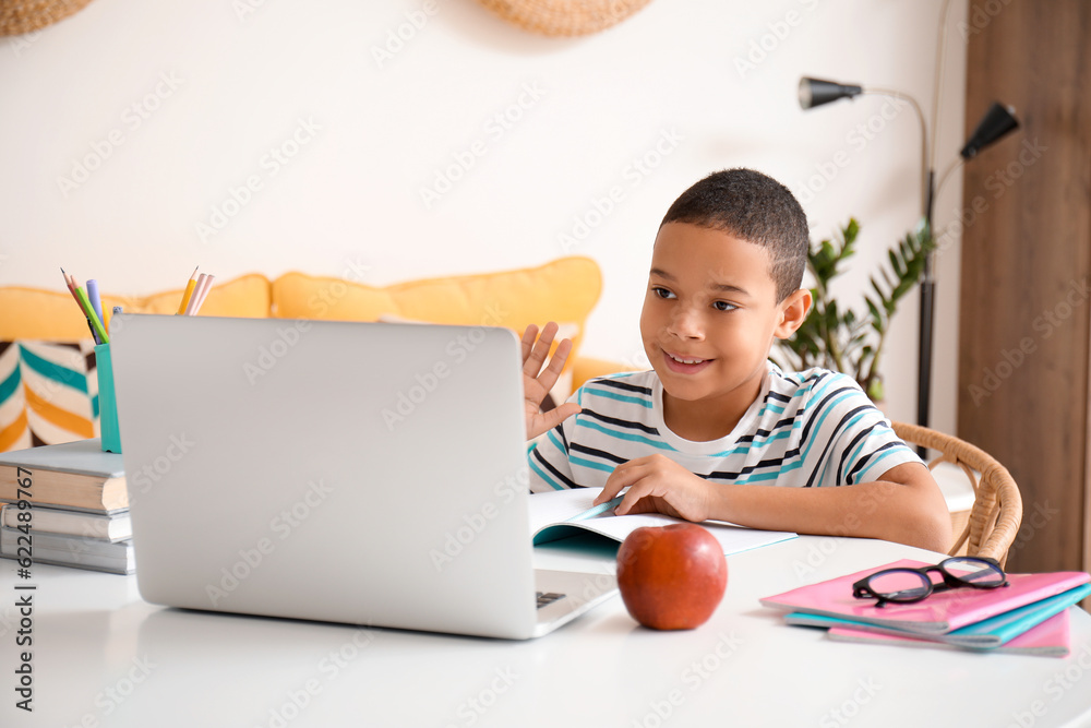 Little African-American boy studying online with laptop at home