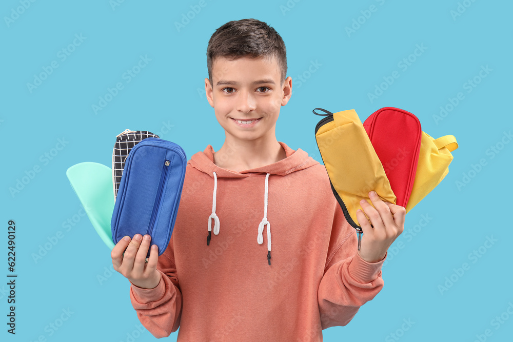 Little boy with pencil cases on blue background