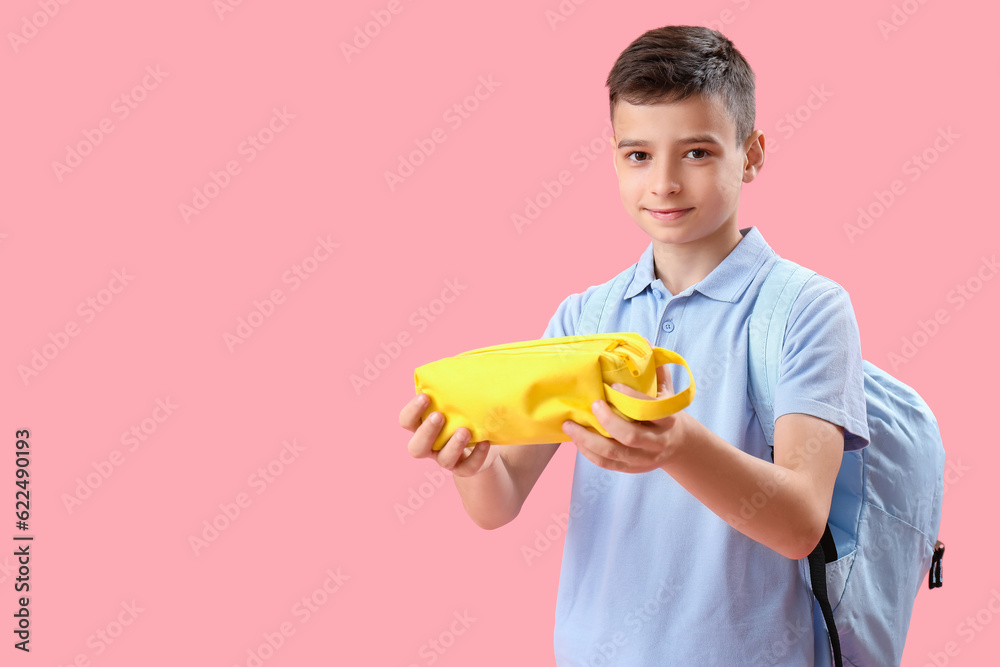 Little schoolboy with pencil case on pink background