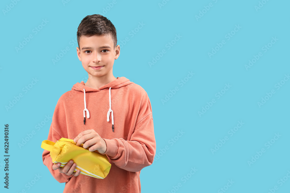 Little boy with pencil case on blue background