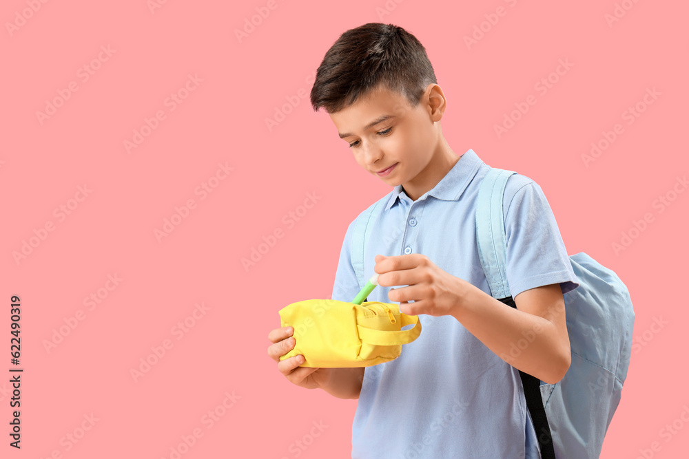 Little schoolboy with pencil case on pink background