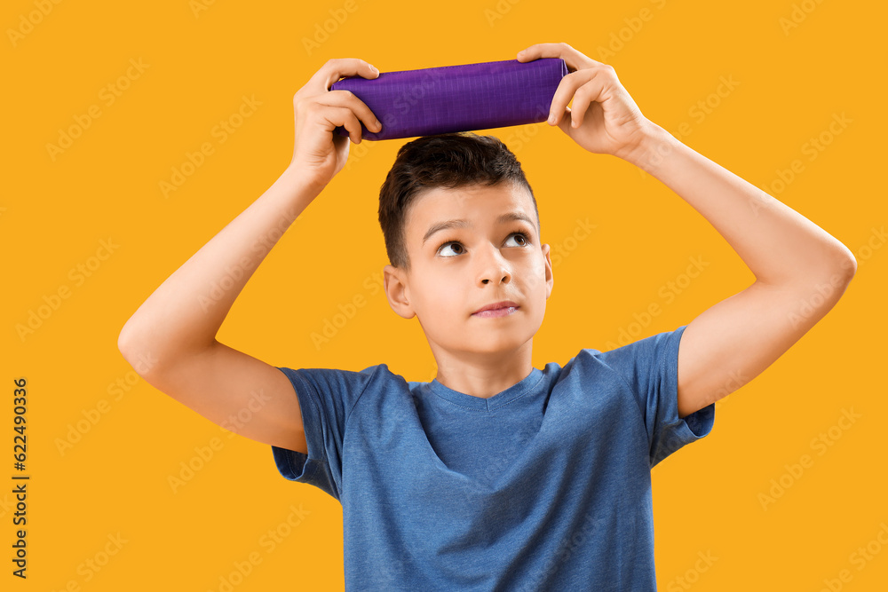 Little boy with pencil case on orange background