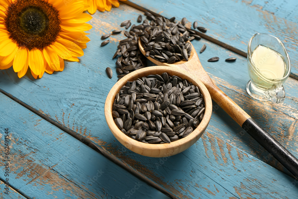 Bowl and spoon with sunflower seeds on blue wooden background