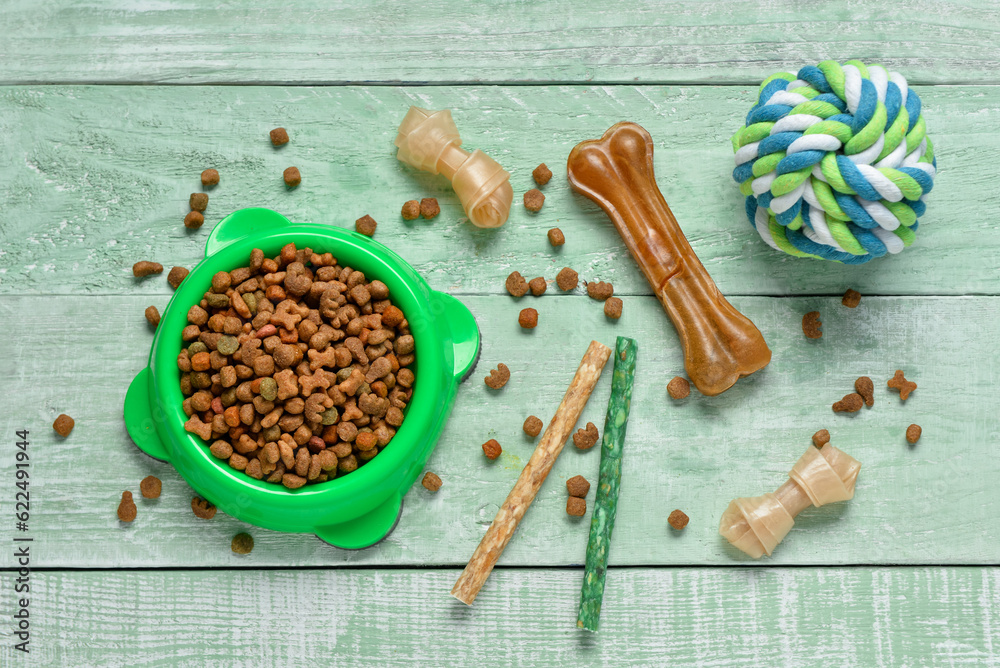 Composition with different dog food and toy ball on color wooden background