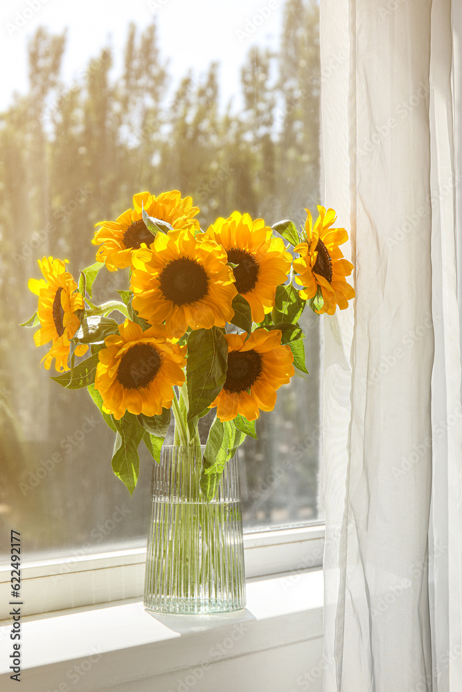 Vase with sunflowers on windowsill in room