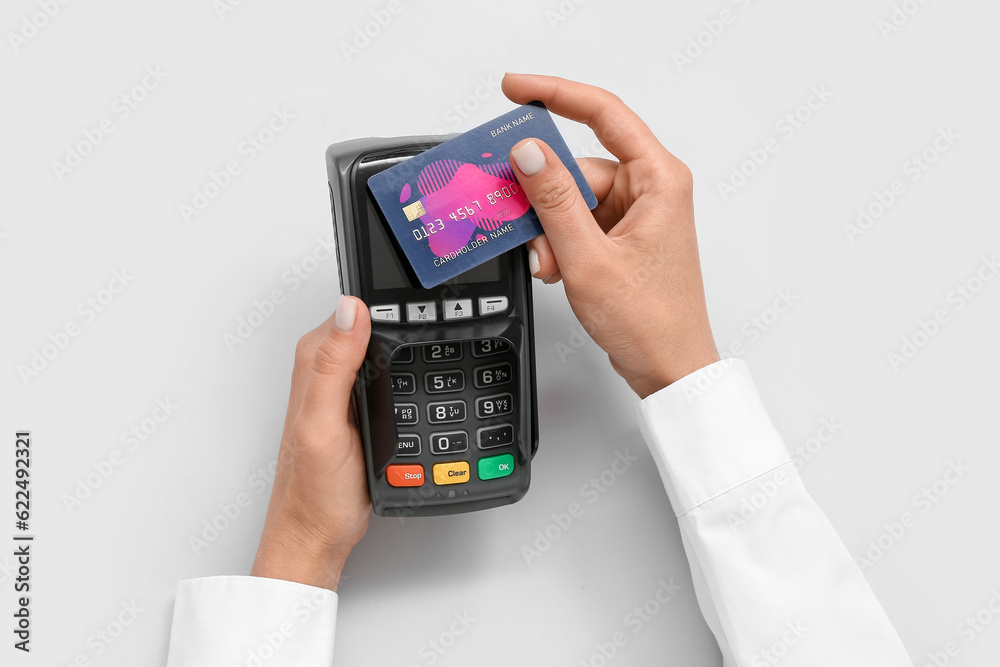 Female hands with credit card and payment terminal on grey background