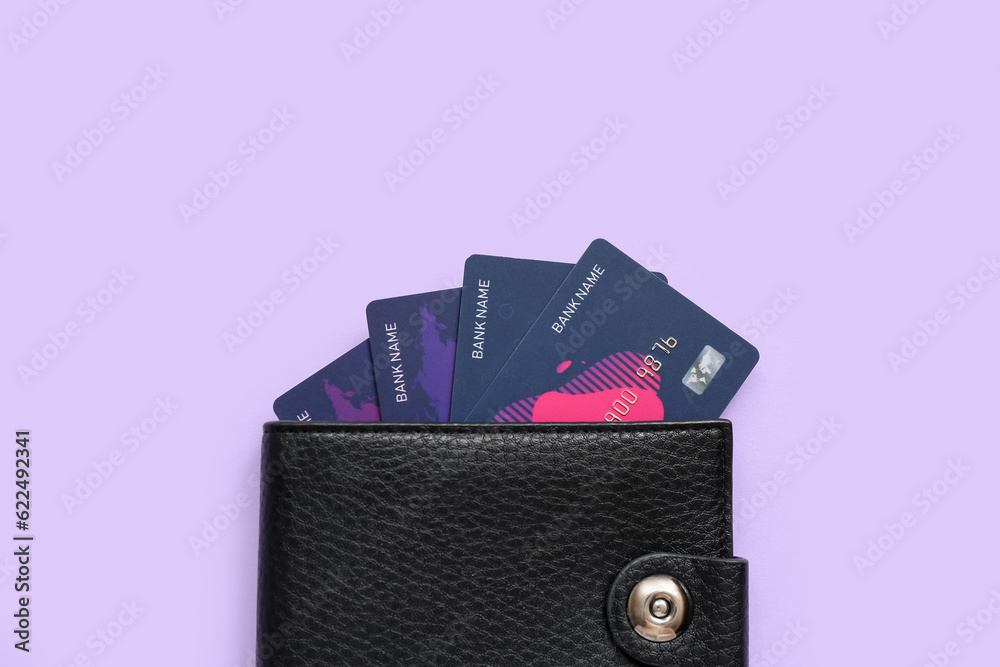 Black leather wallet with credit cards on lilac background