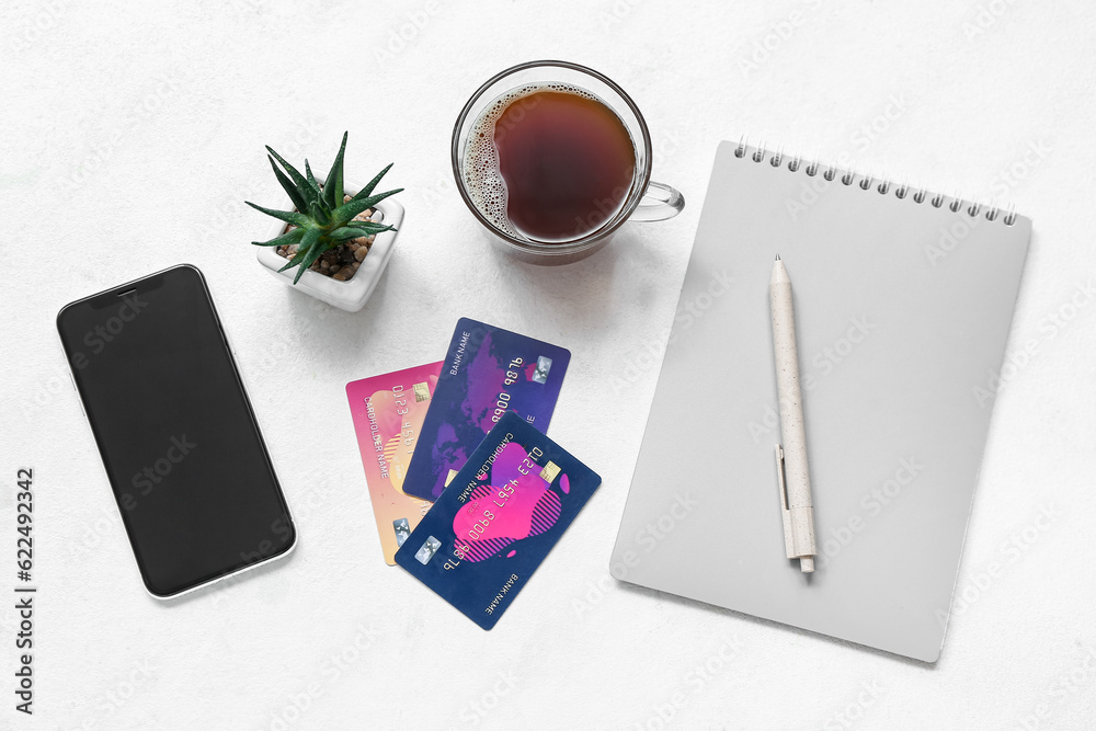 Notebook with cup of coffee, mobile phone and credit card on white background