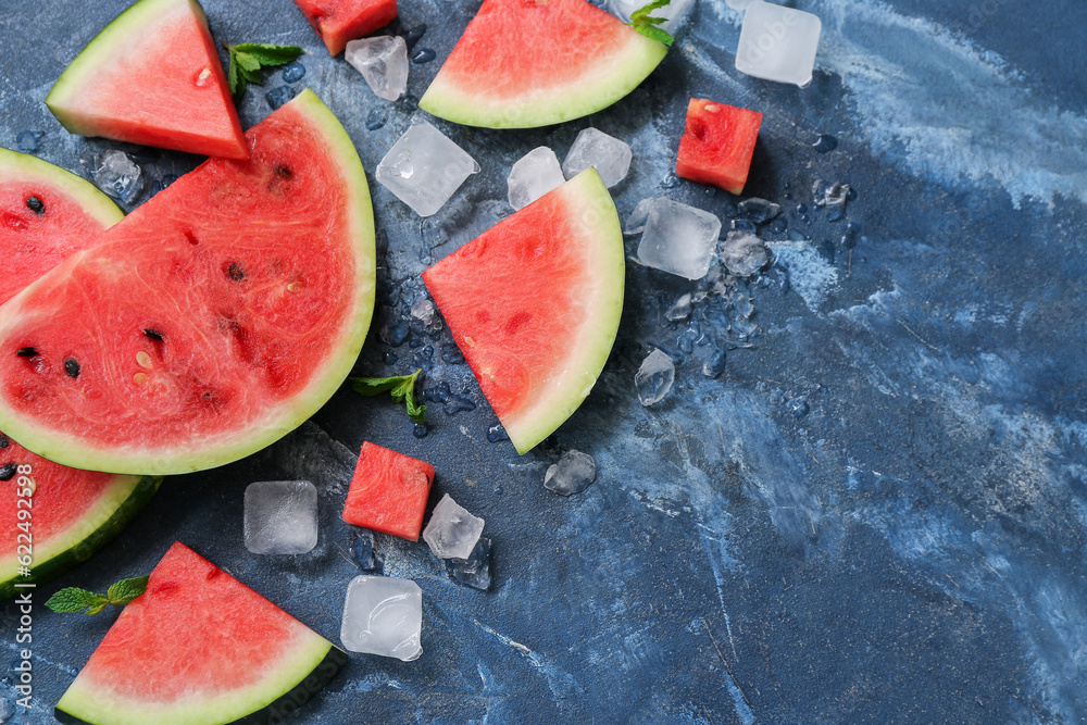 Pieces of fresh watermelon with mint and ice cubes on blue background