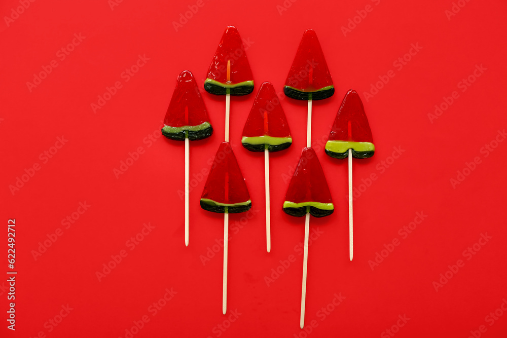 Lollipops in shape of watermelon slice on red background