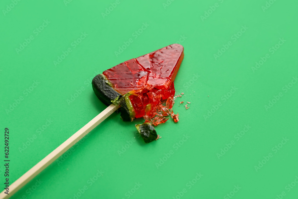 Lollipop in shape of watermelon slice on green background