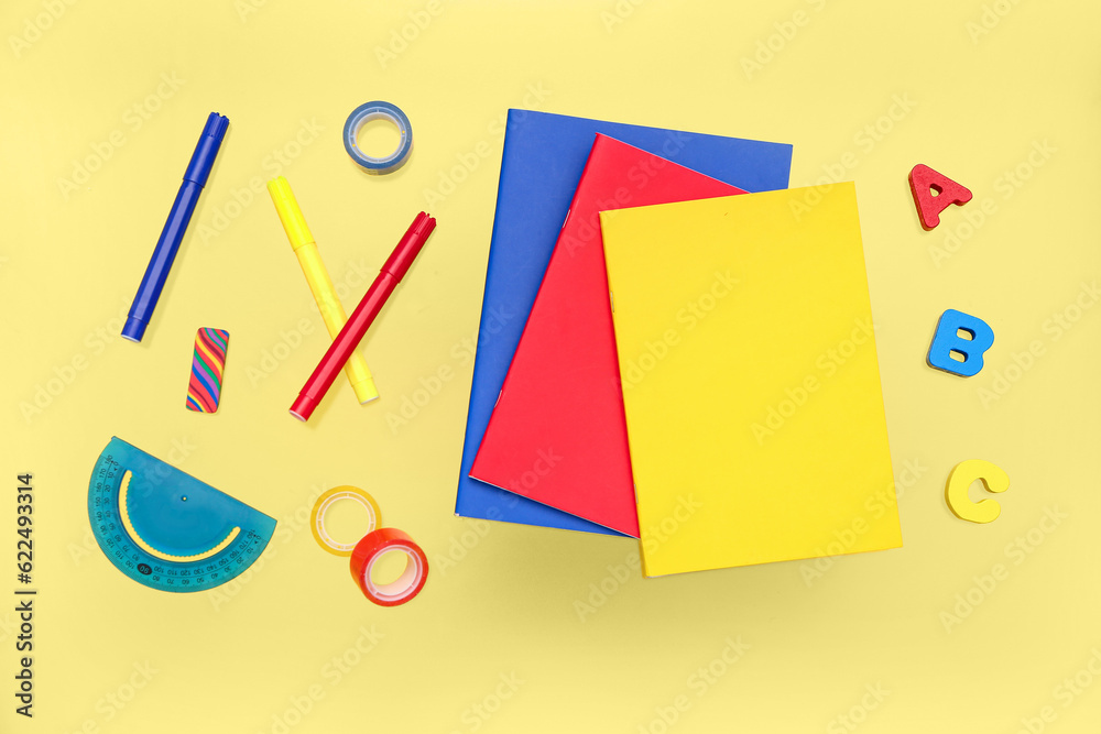 Notebooks with stationery on yellow background