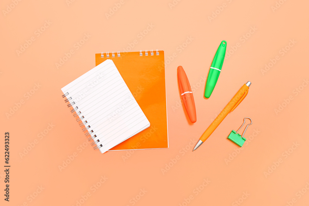 Blank notebook with stationery on orange background