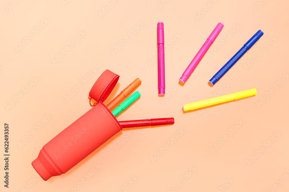 Different colorful markers in case on orange background