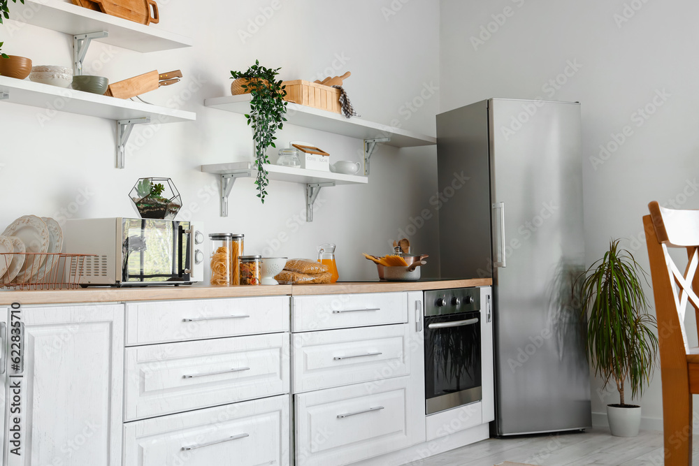 Interior of light kitchen with stylish fridge, counters and shelves