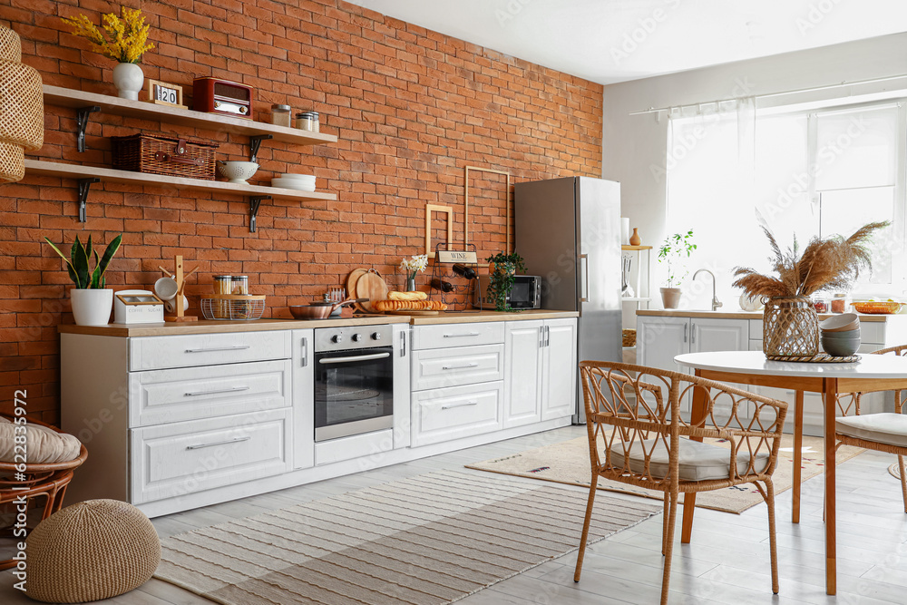 Interior of kitchen with stylish fridge, counters, shelves, table and chairs