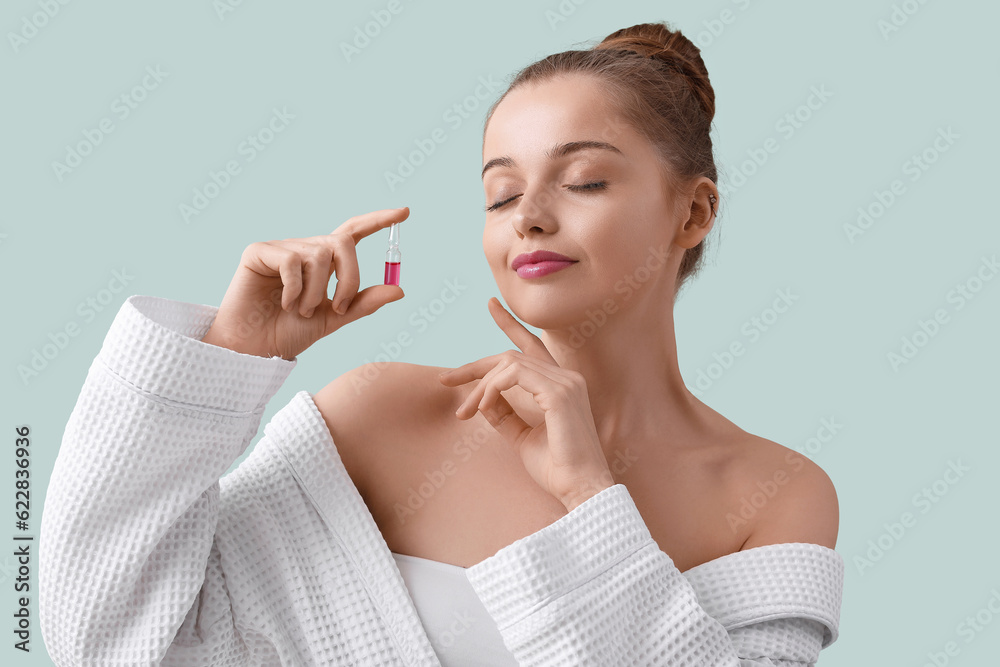 Beautiful young woman with ampule on color background. Skin care concept