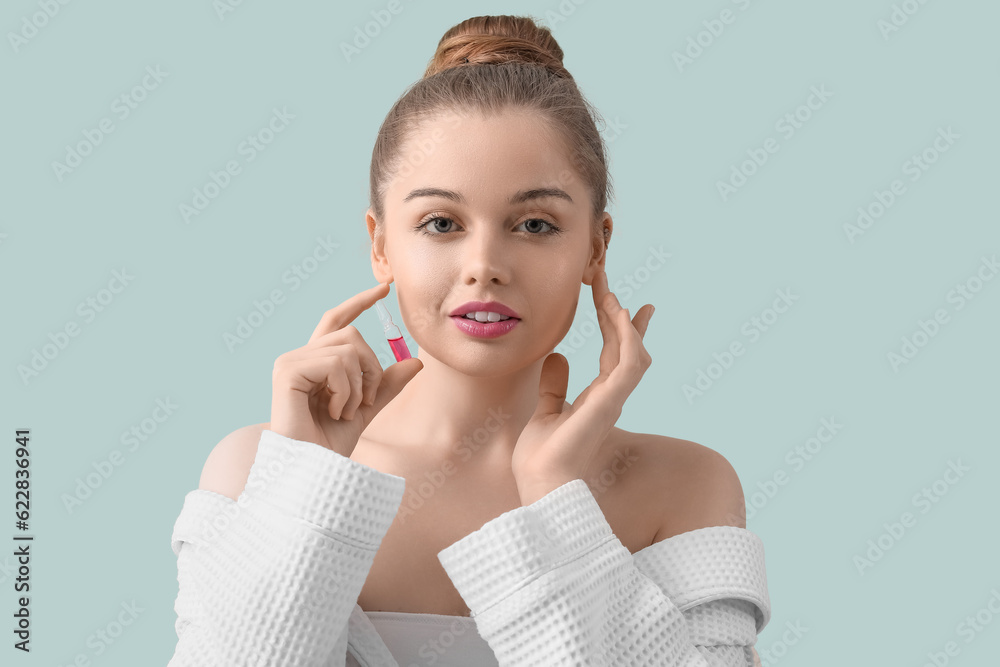 Beautiful young woman with ampule on color background. Skin care concept