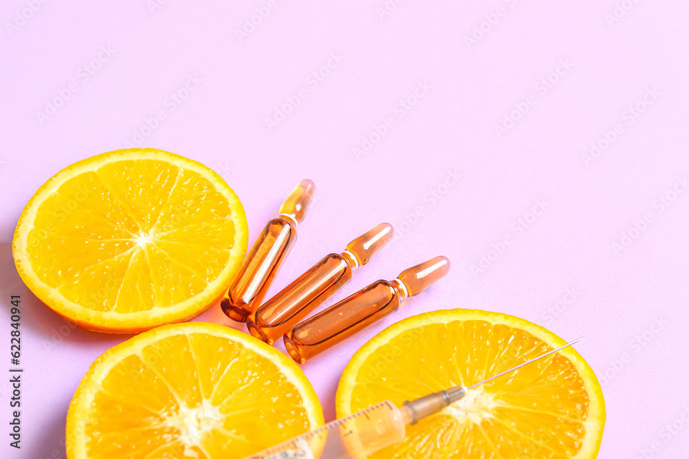 Ampoules with vitamin C, syringe and orange slices on purple background, closeup