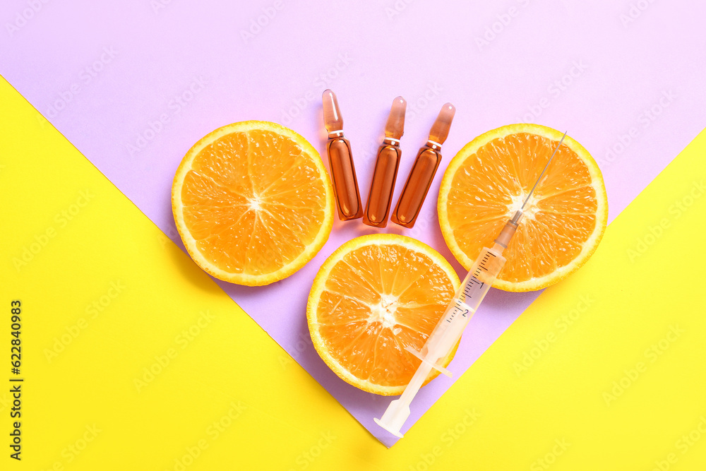 Ampoules with vitamin C, syringe and orange slices on colorful background