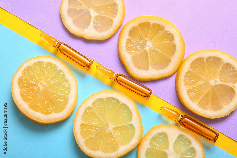 Ampoules with vitamin C and lemon slices on colorful background