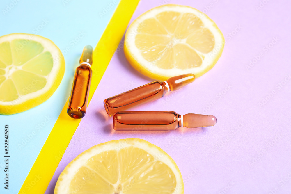 Ampoules with vitamin C and lemon slices on colorful background, closeup