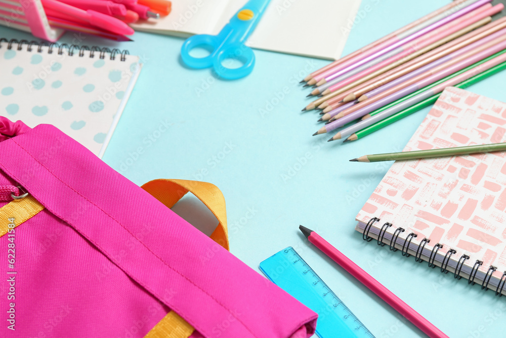 Frame made of school backpack and different stationery on blue background, closeup