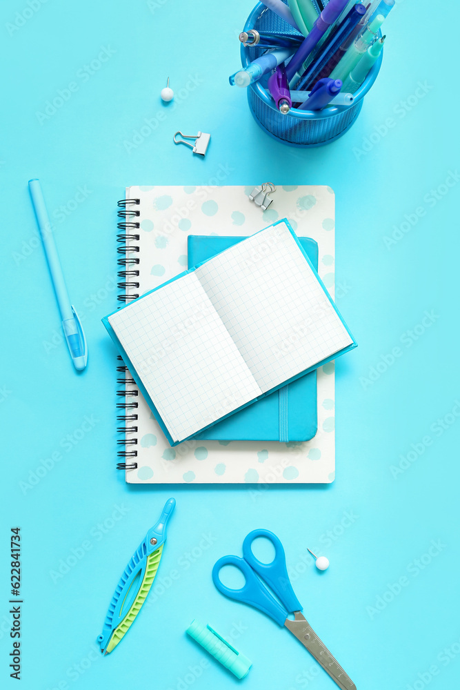 Composition with notebooks and different school stationery on blue background