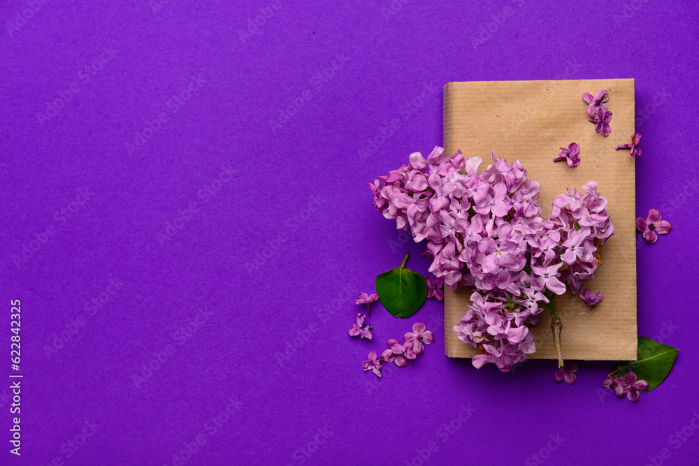 Beautiful lilac flowers and book on purple background